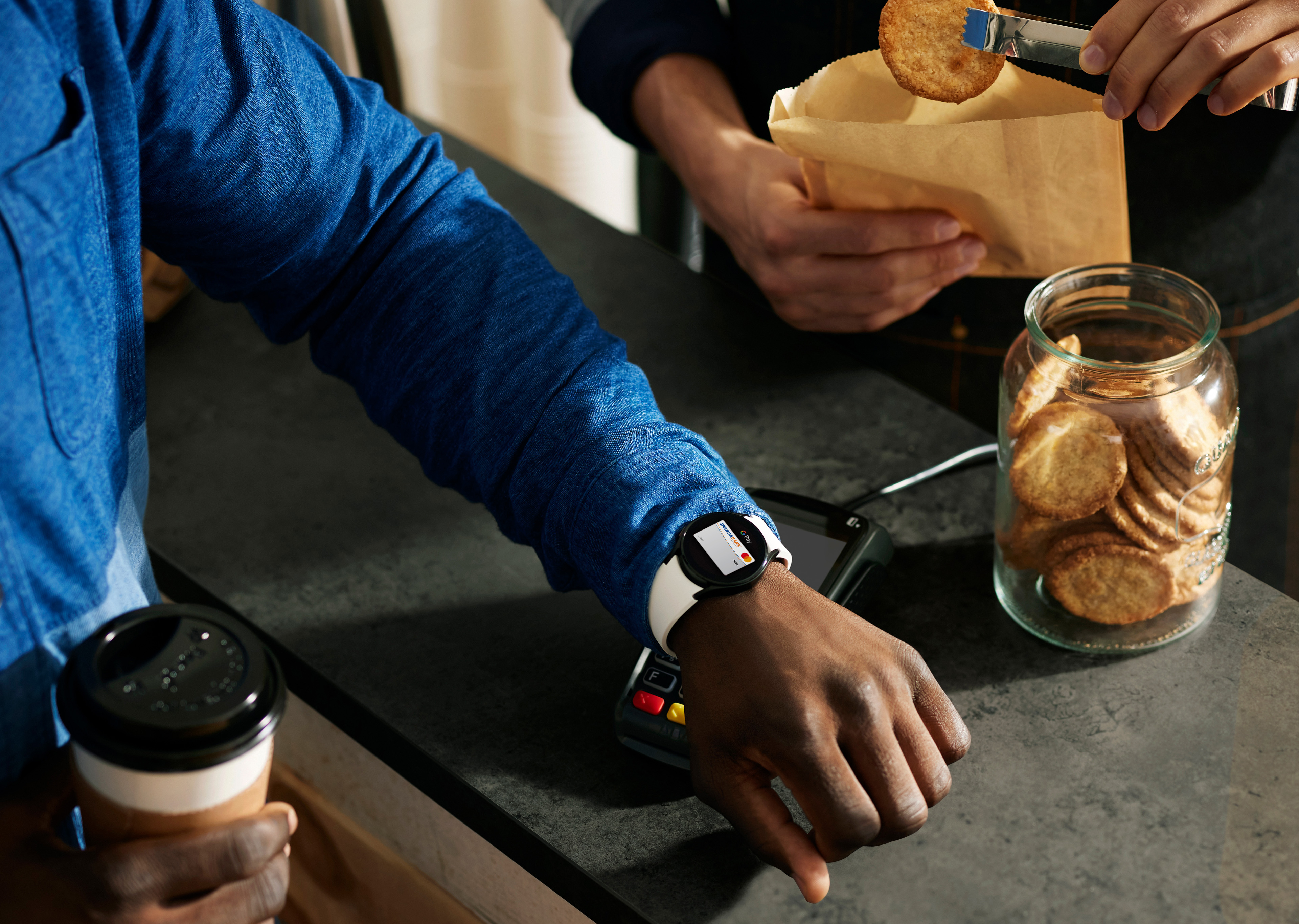 Mann bezahlt mit Uhr an der Kasse man sieht nur den Arm und die Hand