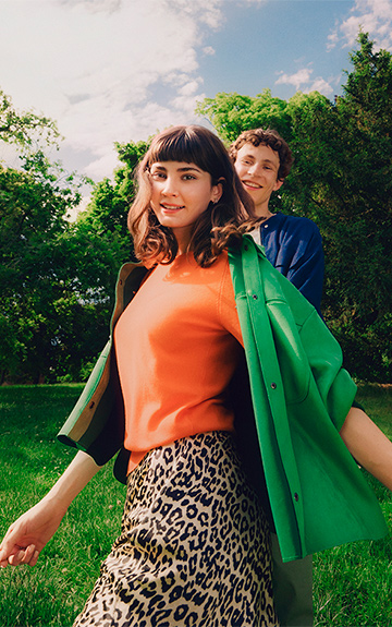 Eine Frau auf einer Wiese, hinter ihr sieht man Bäume.